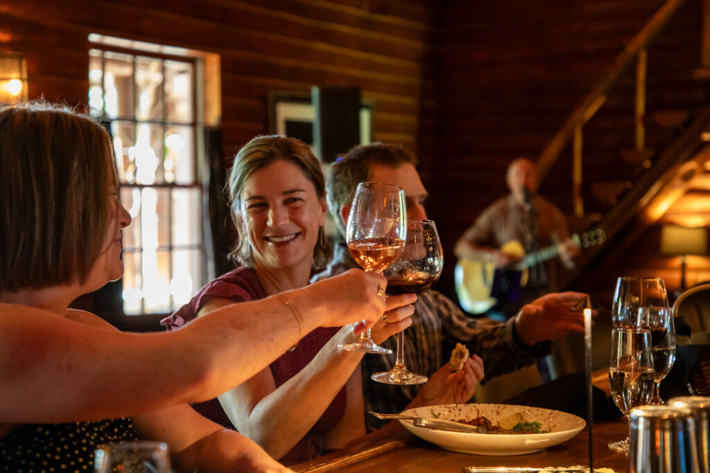 Two women smiling while they cheers with glasses of wine in restaurant.